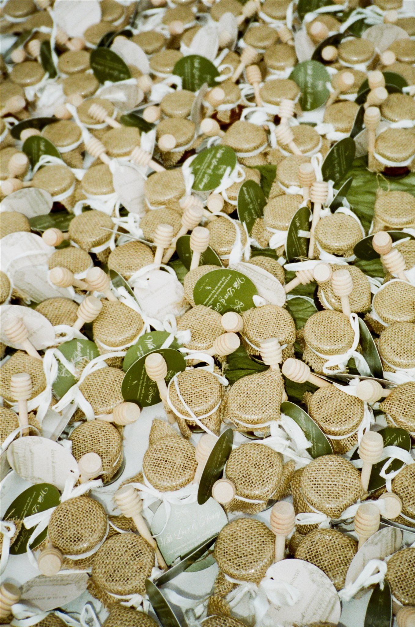 A large collection of soap bars with honey dipper sticks and green tags attached, arranged in a display.