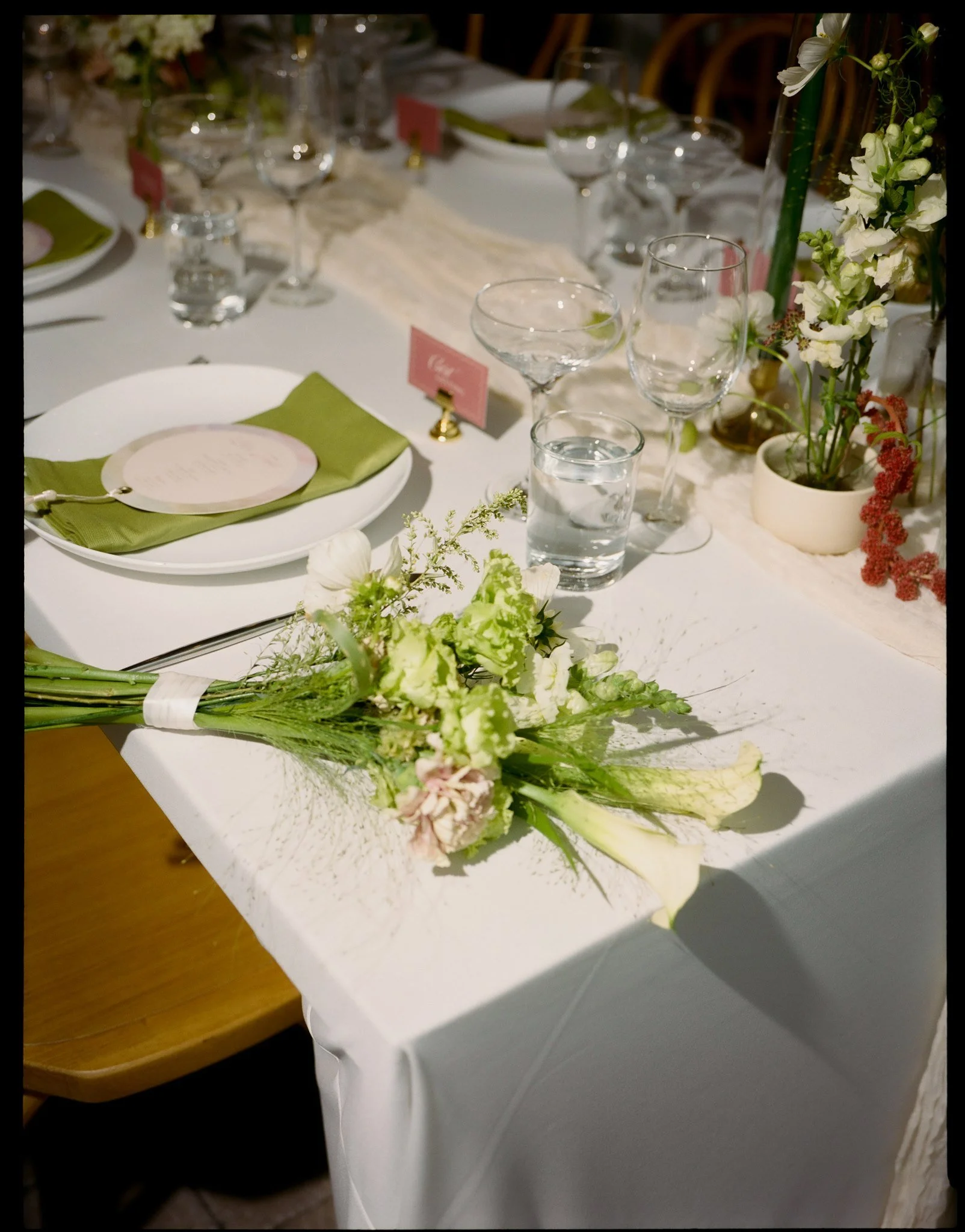 A decorated dining table with glassware, plates, floral centerpieces, and place settings in a formal setting.