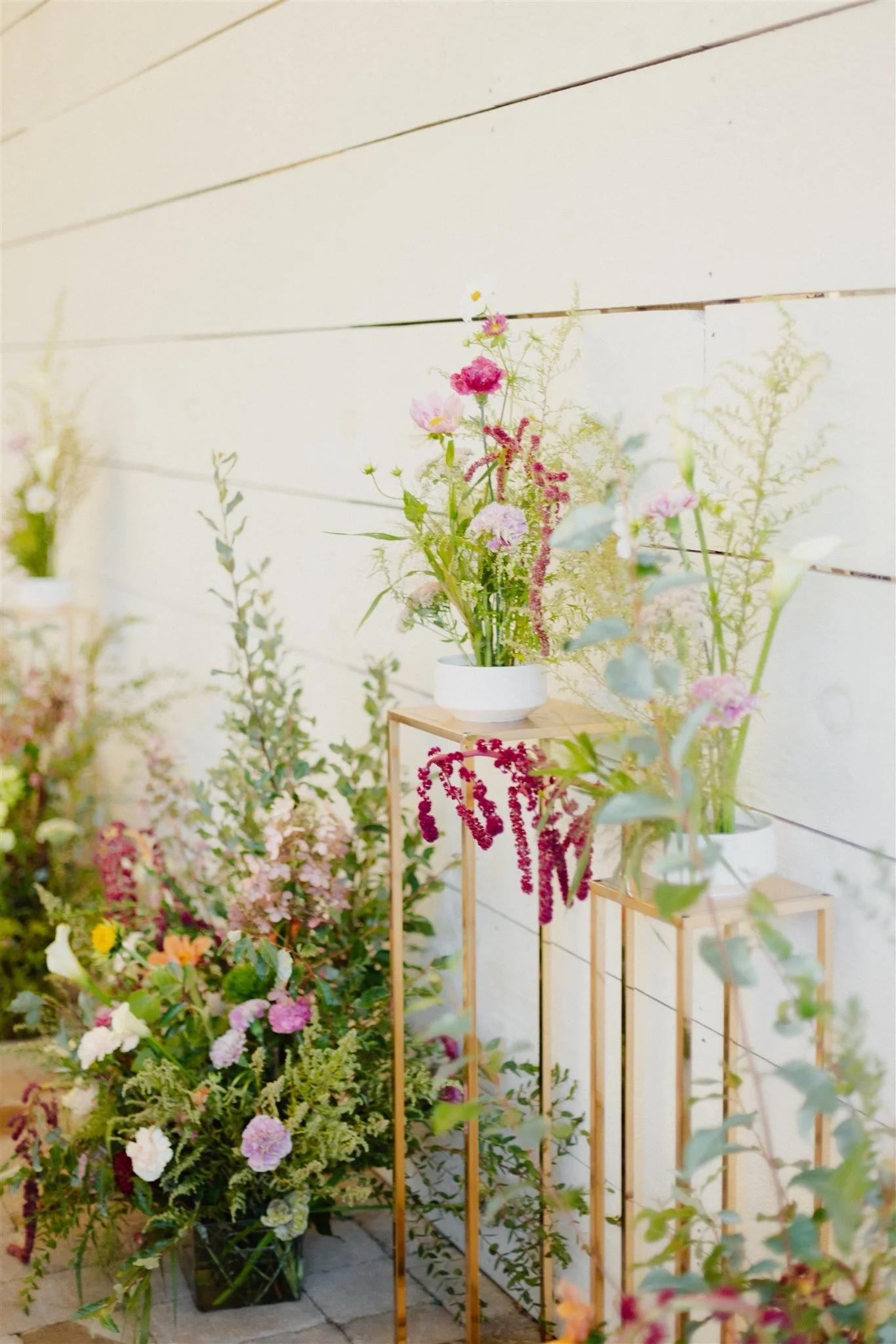 A display of colorful flowers arranged on wooden stands against a white wall.