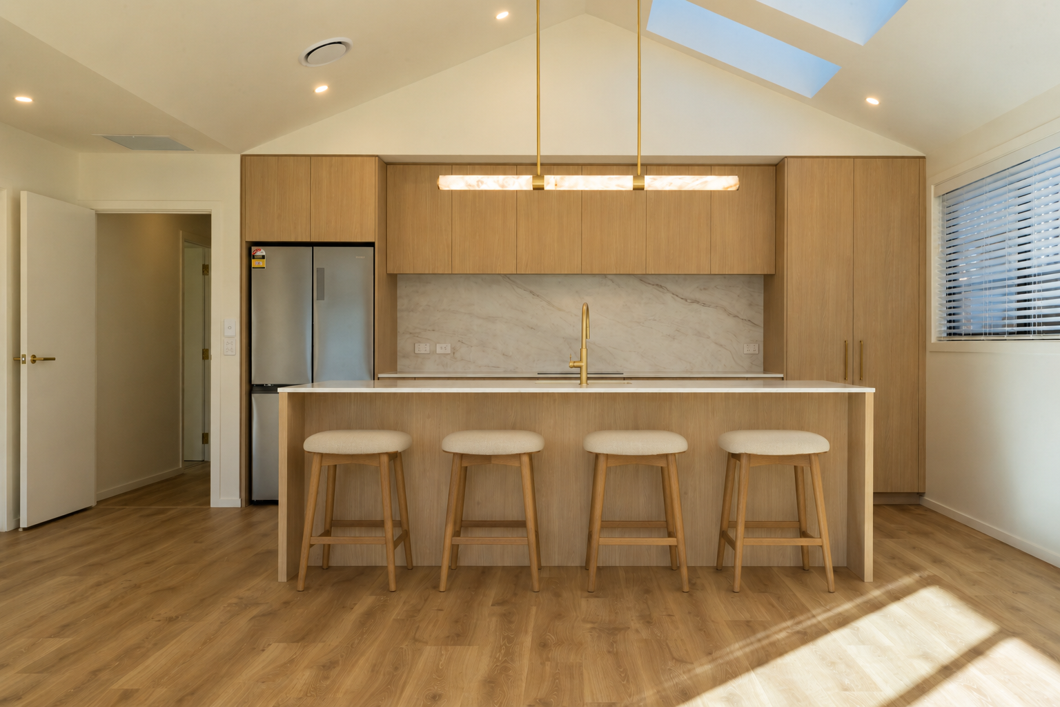 Designer kitchen with a large stone island, custom cabinetry, integrated storage, and contemporary finishes, highlighting thoughtful interior design in a Queenstown home.