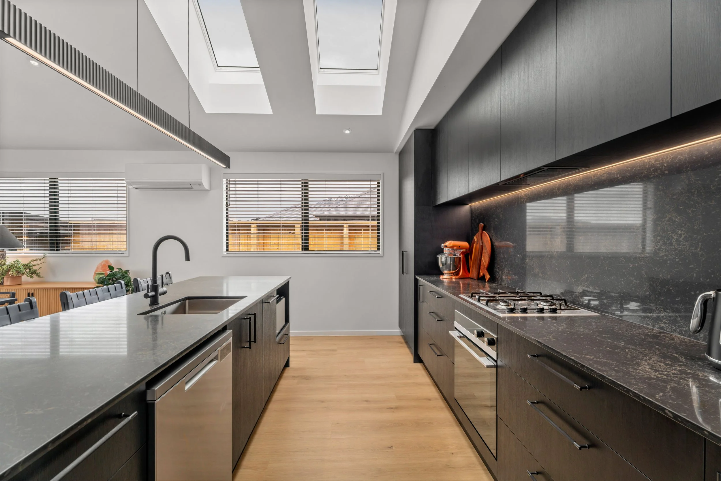 Modern kitchen with black timber cabinetry, stone benchtops, and soft neutral finishes. Contemporary interior design by Nova Design Studio in Queenstown, New Zealand.