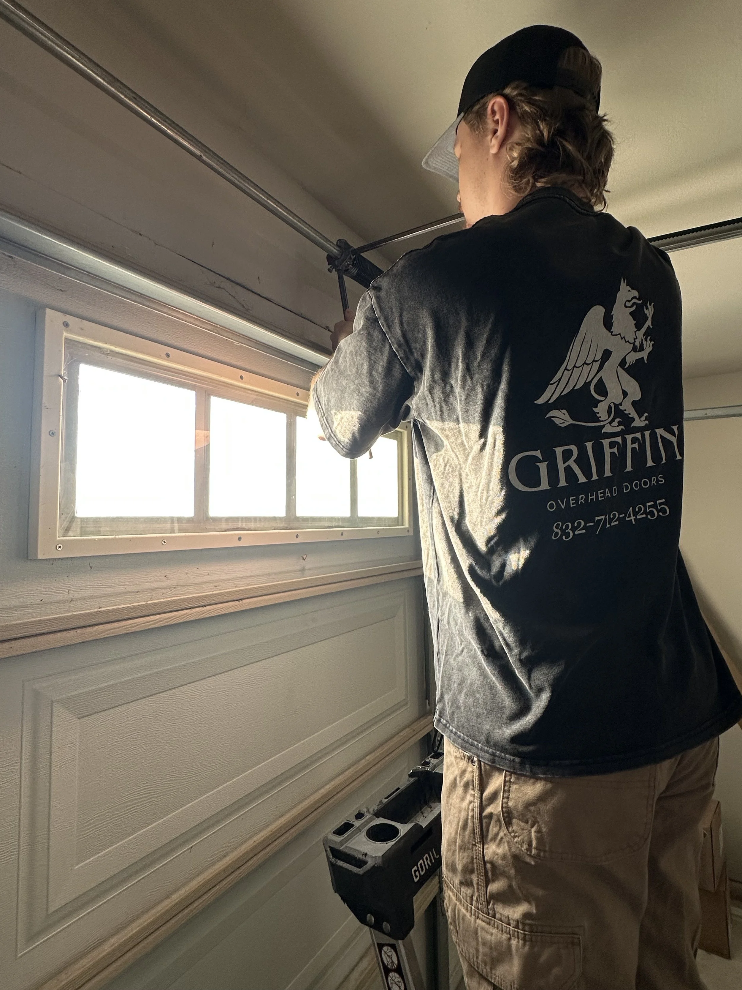 The owner of Griffin Overhead Doors repairing a spring on a garage door.