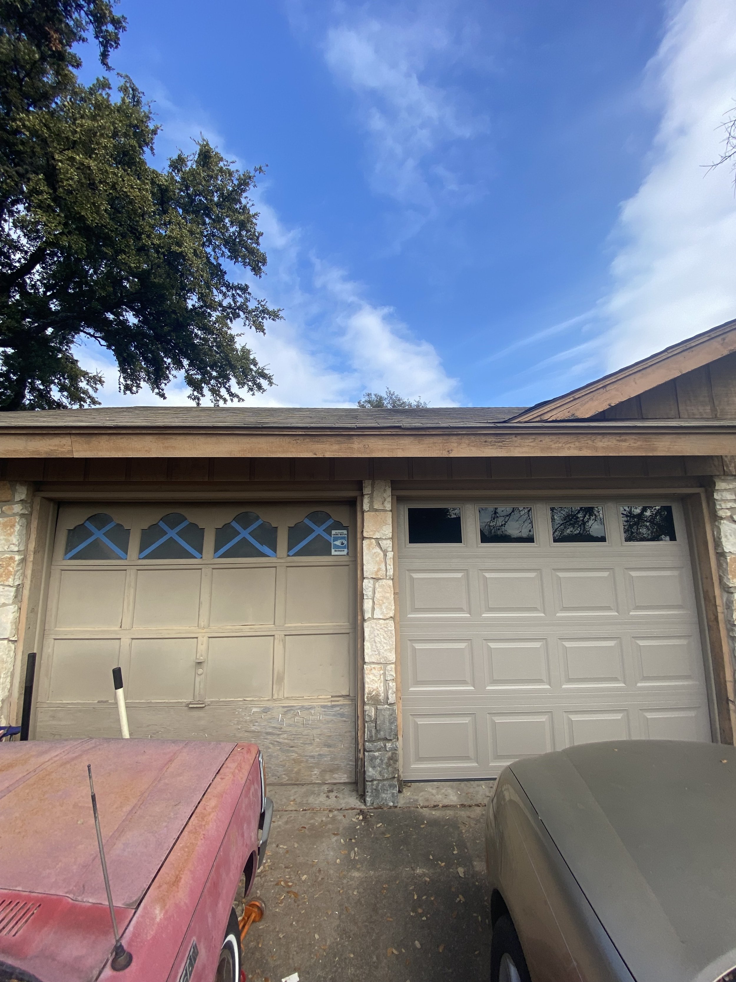 A pair of installed garage doors side by side. The left garage door is an old wooden door that has been rotting and has broken windows across the top. The right garage door is modern, freshly installed, and offers greater curb appeal.