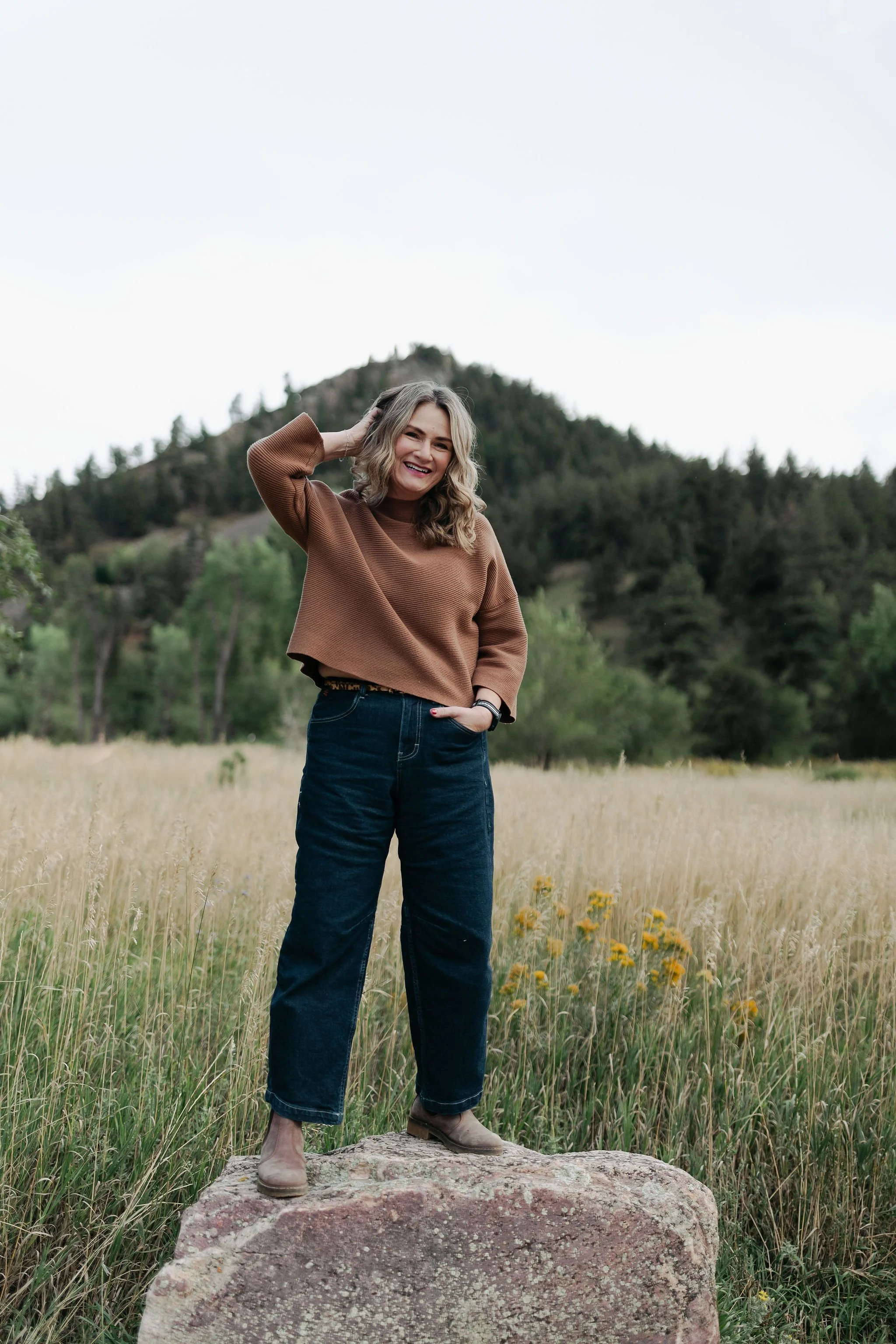Jill Krush outdoors in a mountain field, offering a warm and grounded presence that guides her supervision and consultation work.