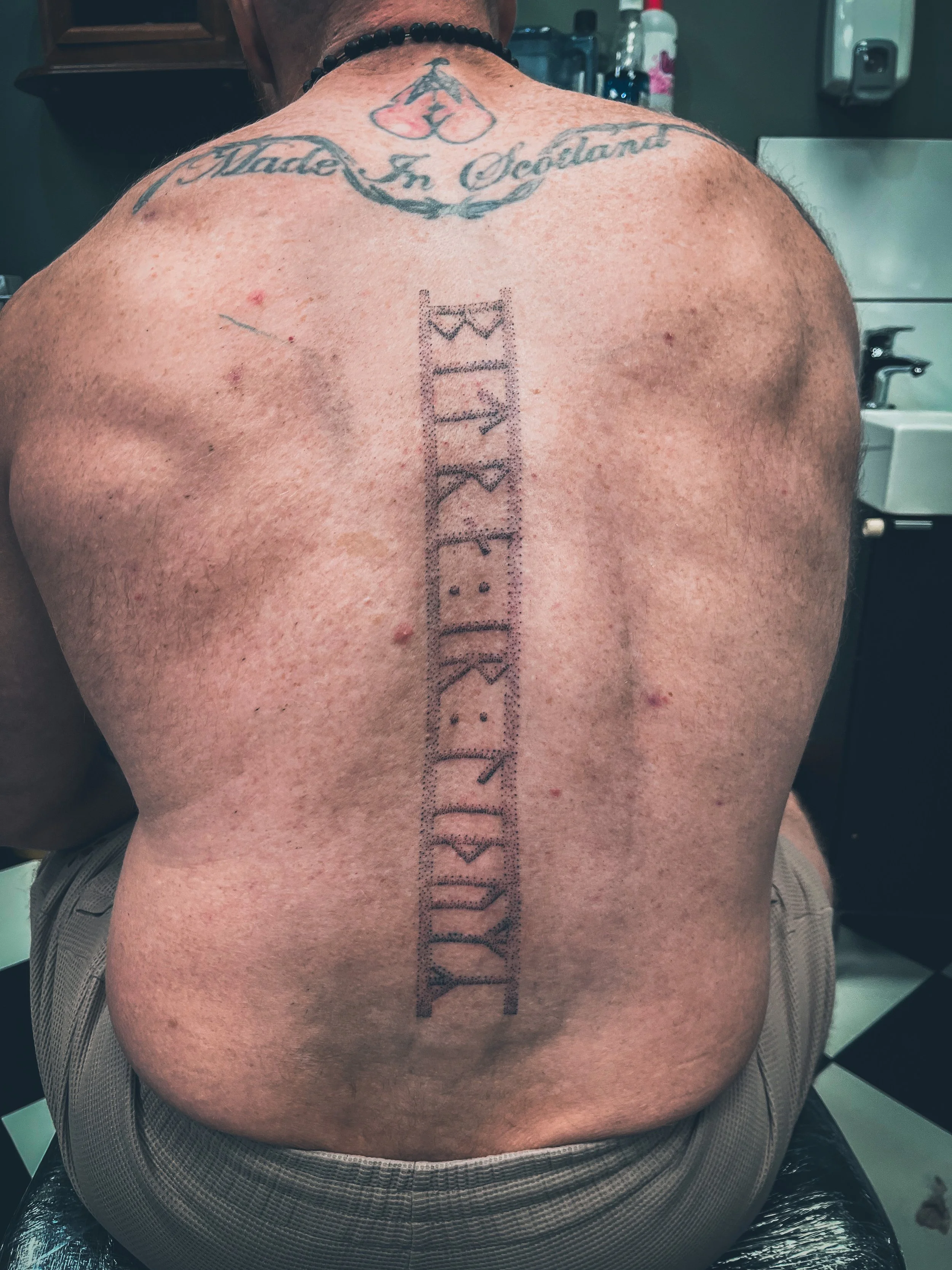 Hand Poked Traditional Tattoo in Cincinnati Ohio done at Stag and Castle in Mt Lookout of a Runic Inscription of Nordic Norse Heathen Paganism on the back of a body builder 