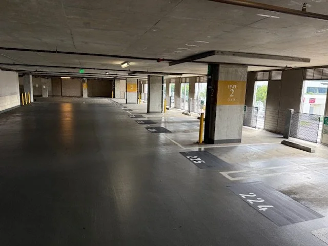 Empty multi-level parking garage with marked parking spaces and support columns. Parking structure