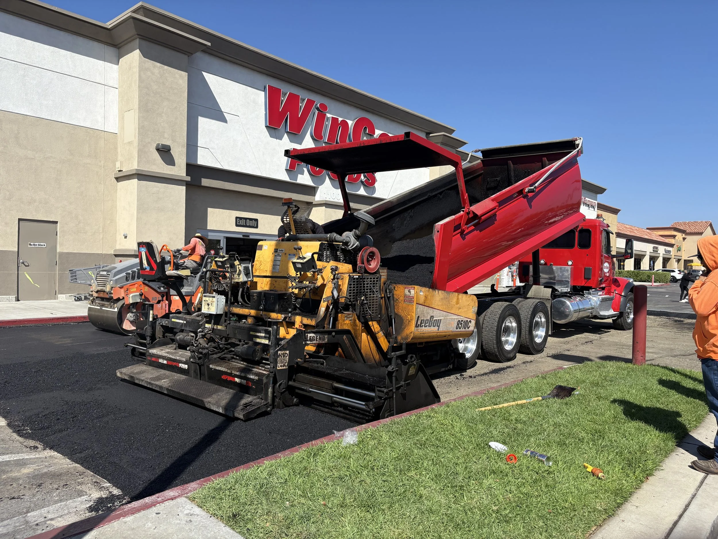 A construction scene outside a building using a paving machine to do a new asphalt parking lot. parking lot maintenance and lot management. Riverside county