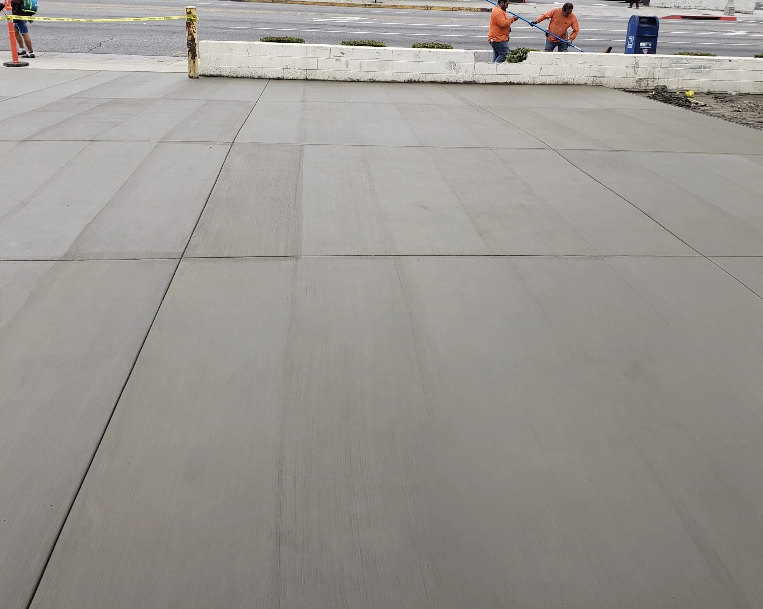 Newly poured concrete sidewalk in front of a construction site. New driveway and parking area with new flat concrete and perfect joints. Pasadena, Los Angeles