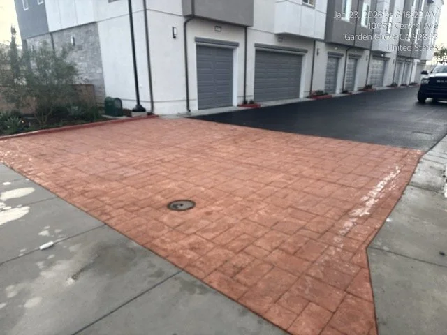 Empty stamped concrete entrance next to a building with garages.