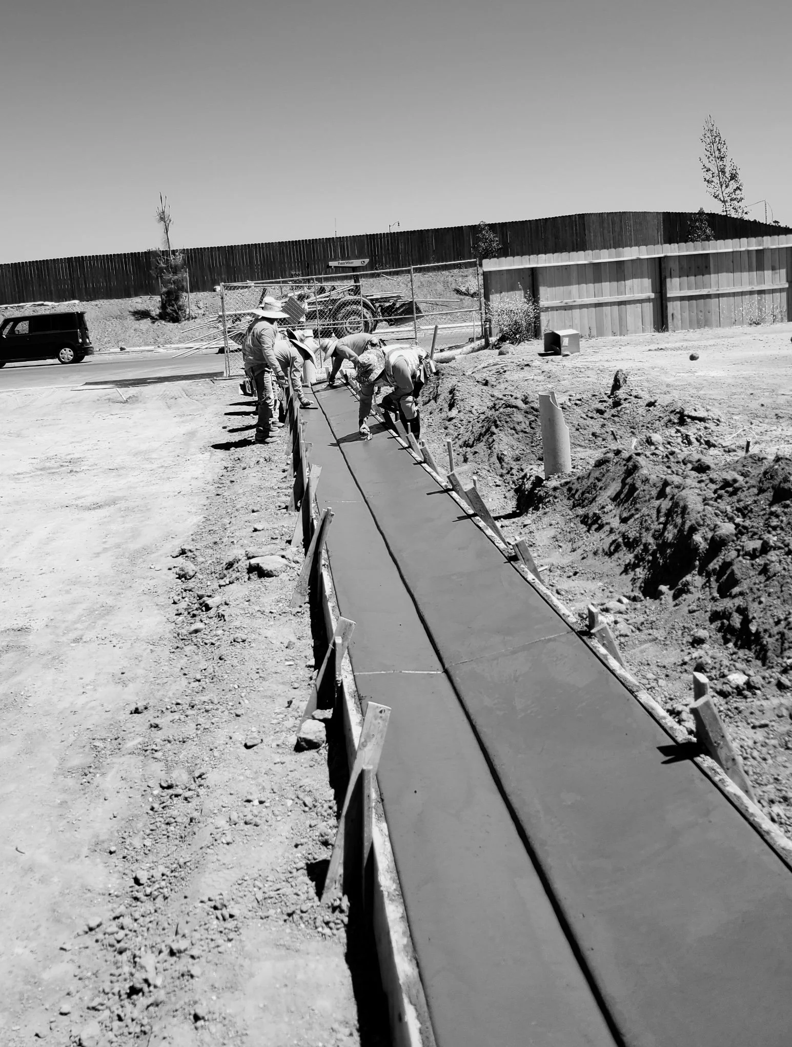 Workers smoothing concrete sidewalk on a construction site.