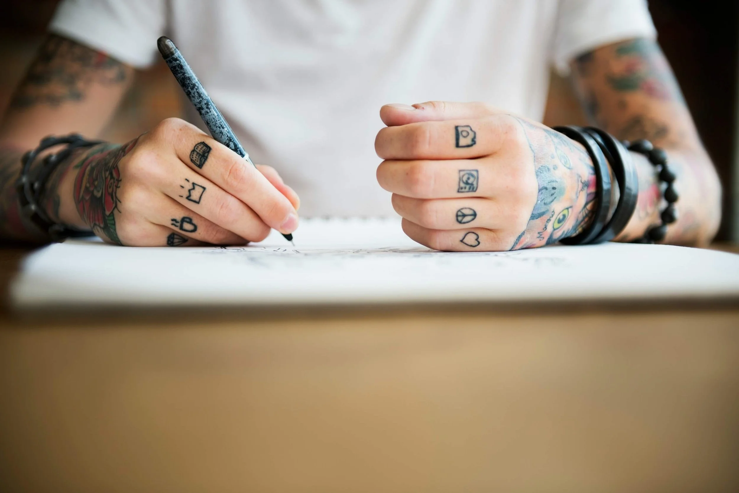 person writing with finger tattoos