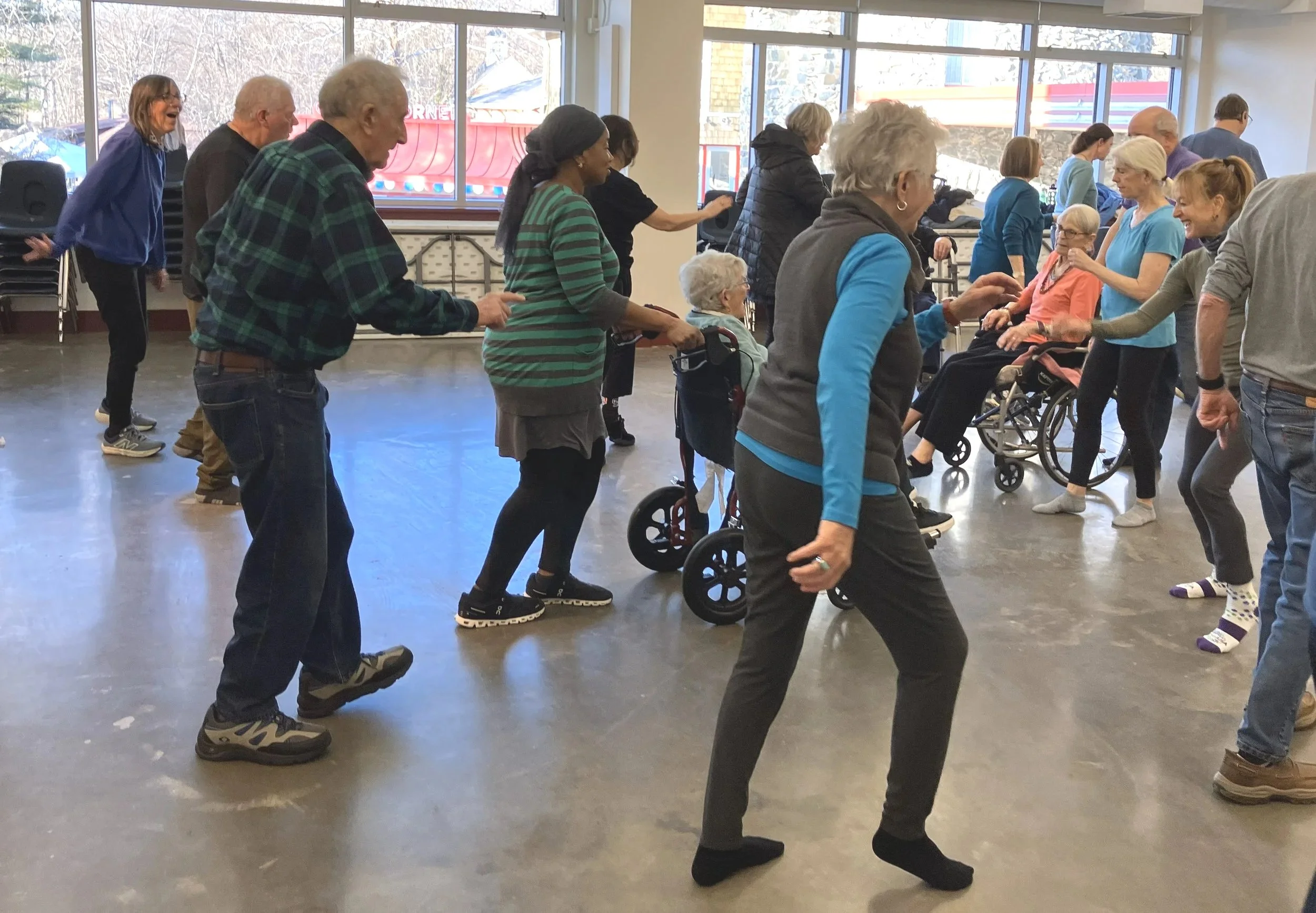 Group of Dance for PD dancers dancing together in a large indoor space at Glen Echo Park with large windows, enjoying the class