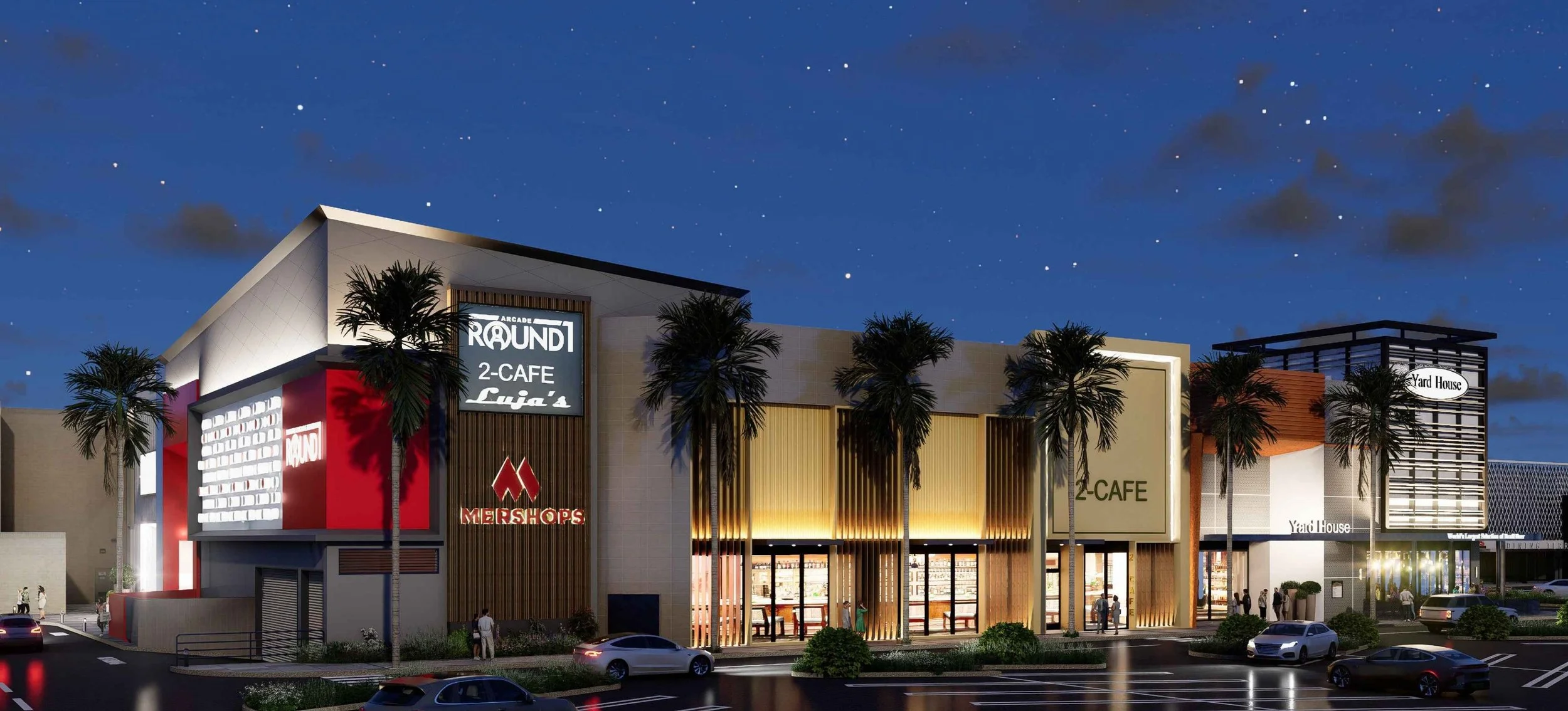 Nighttime view of a modern shopping mall with signs for various businesses, including a cafe, arcade, and yard house, illuminated by exterior lights and surrounded by palm trees and parked cars. Structural engineering by BASE Design in San Francisco.