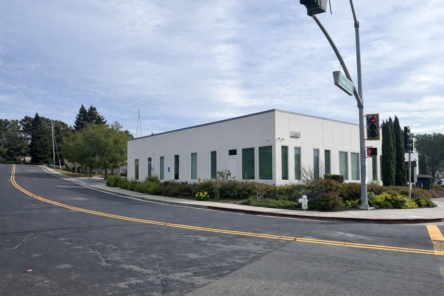 A modern white building with tall, narrow windows sits on a street corner, surrounded by well-maintained landscaping. Structural engineering by BASE Design in San Francisco.