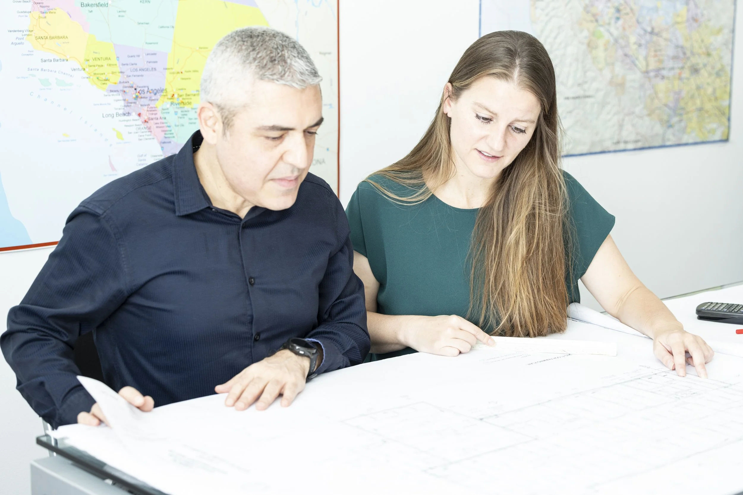 From Left to Right: BASE Design cofounders Gokhan Akalan and Katy Briggs review planning documents side by side from their San Francisco office.