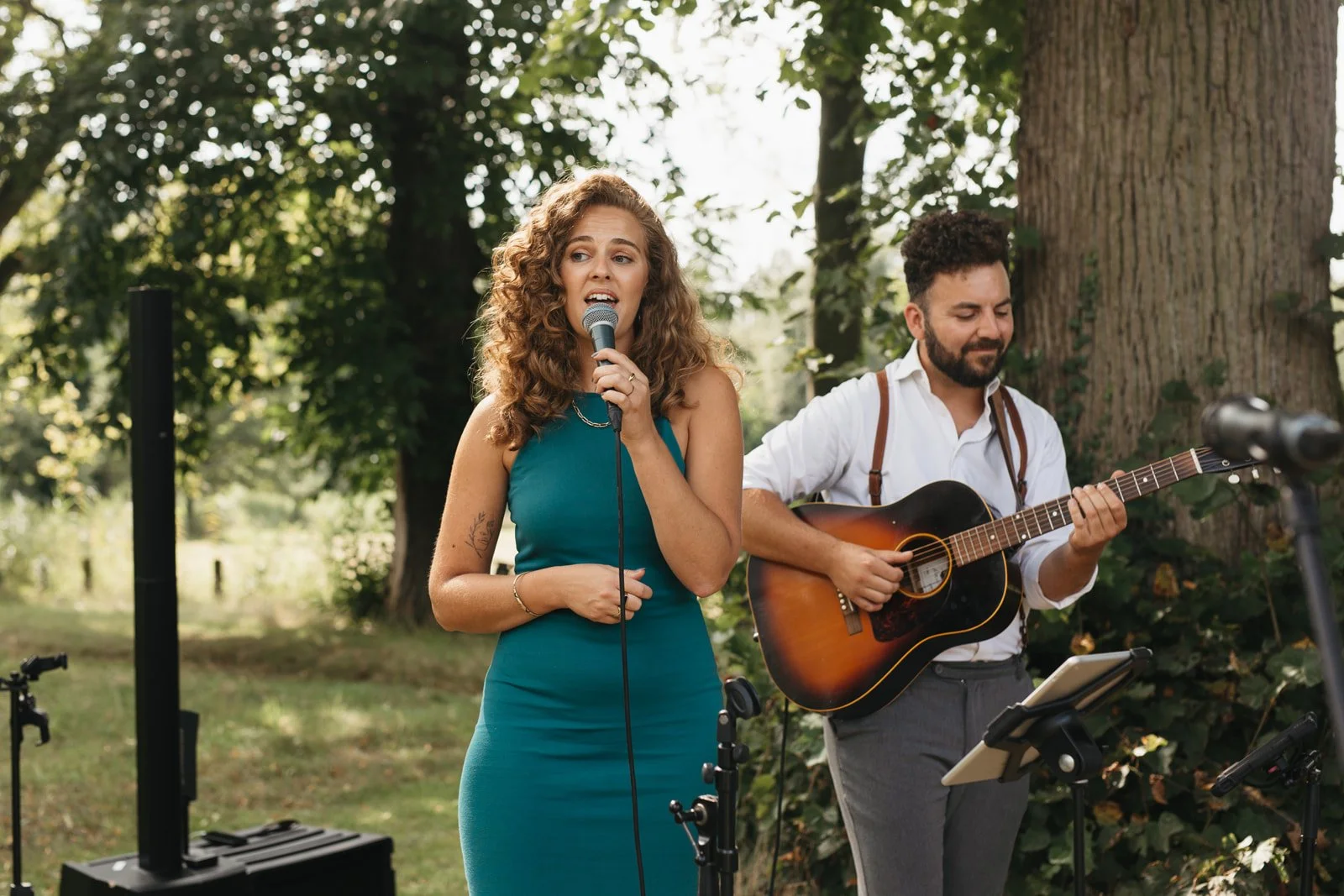 Zangeres en gitarist spelen live muziek in de zomer tijdens een bruiloftsborrel. Muzikanten van Mr. Allegaartje.