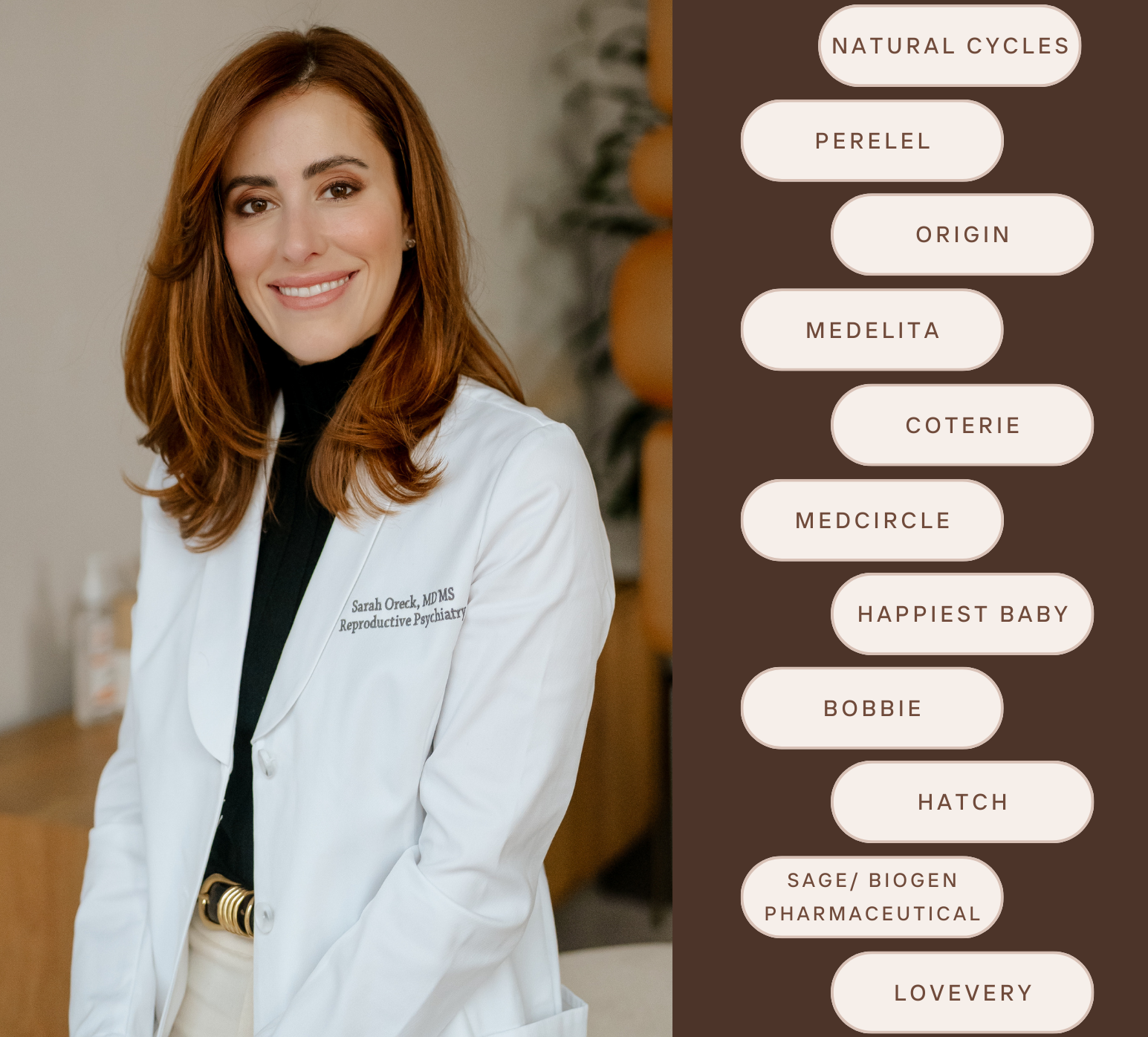 Dr. Oreck with shoulder-length red hair, smiling, wearing a white coat with her name and credentials embroidered on her white coat, standing indoors.