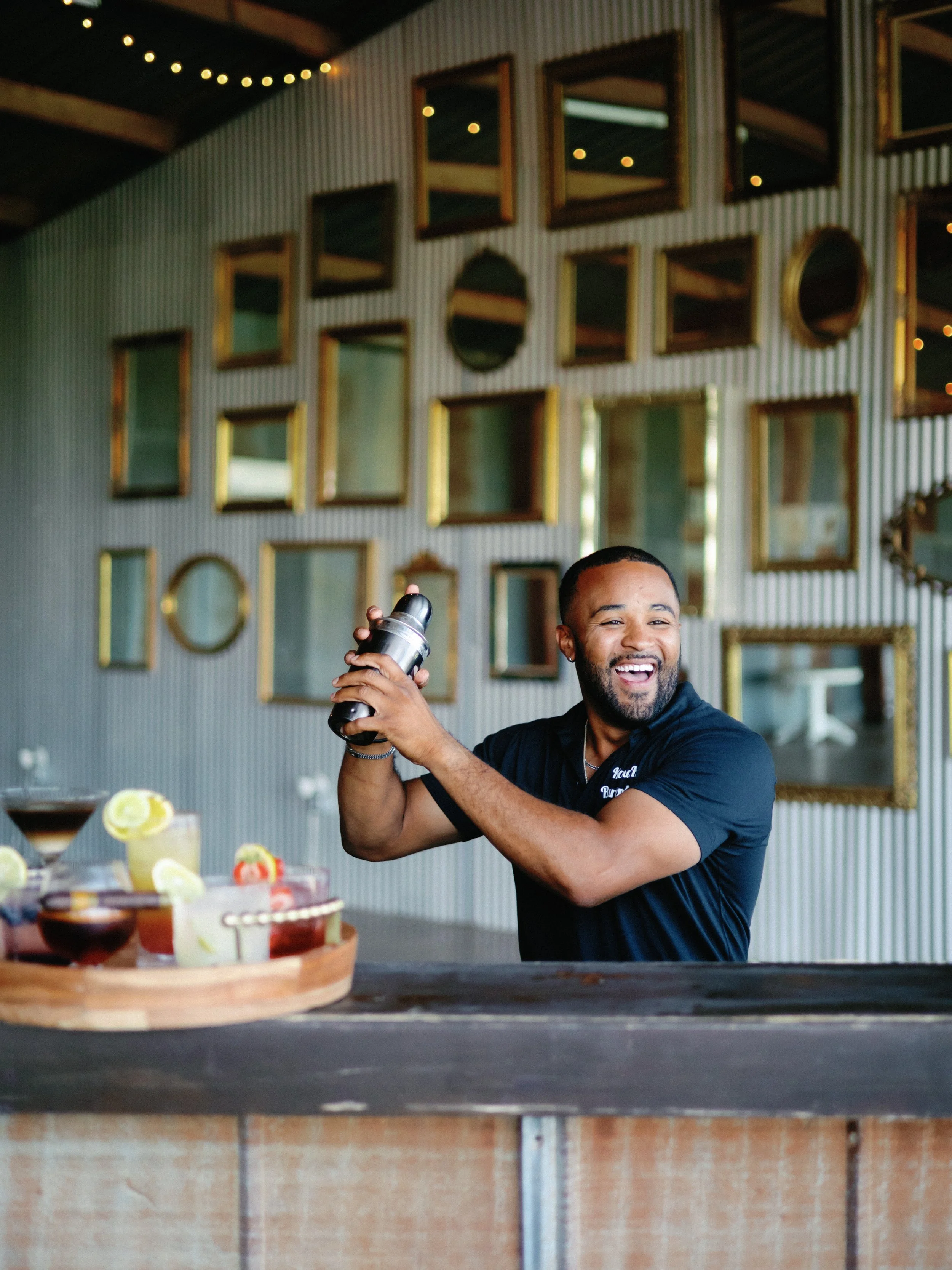 Bartender Sway from K&K Bartending smiling while shaking a cocktail behind the bar at Kitalou Gin.