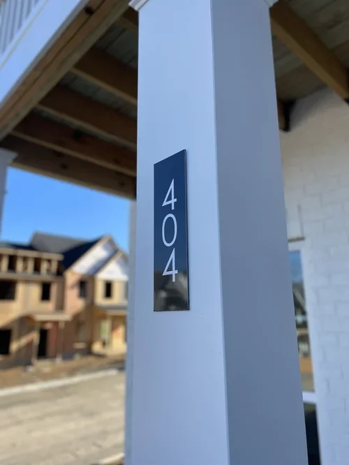 Close-up of a white porch column with house number 404 on a black plaque.