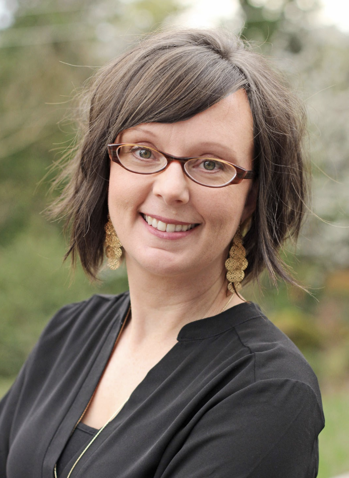 Two people holding hands, one wearing a dark shirt and light-colored pants, and the other wearing a brown dress.