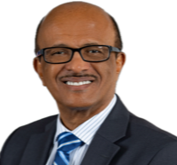 A middle-aged man with glasses, smiling, dressed in a suit and tie, against a plain background.