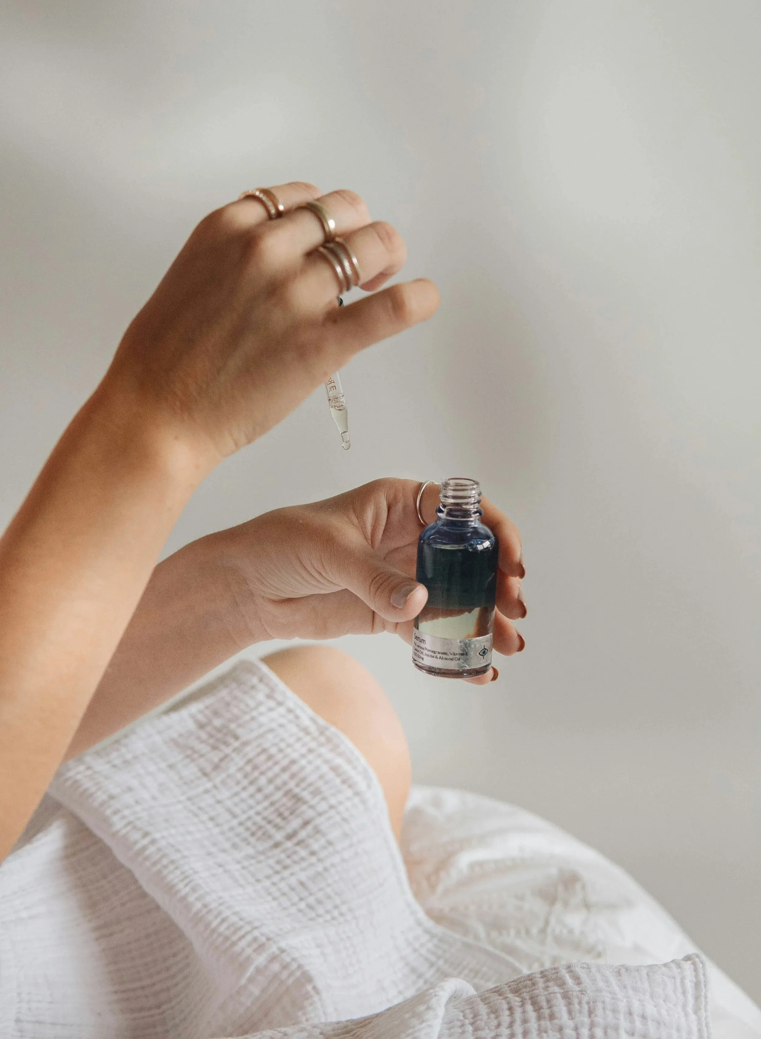 Person holding a small bottle and using a dropper to dispense liquid into the bottle.