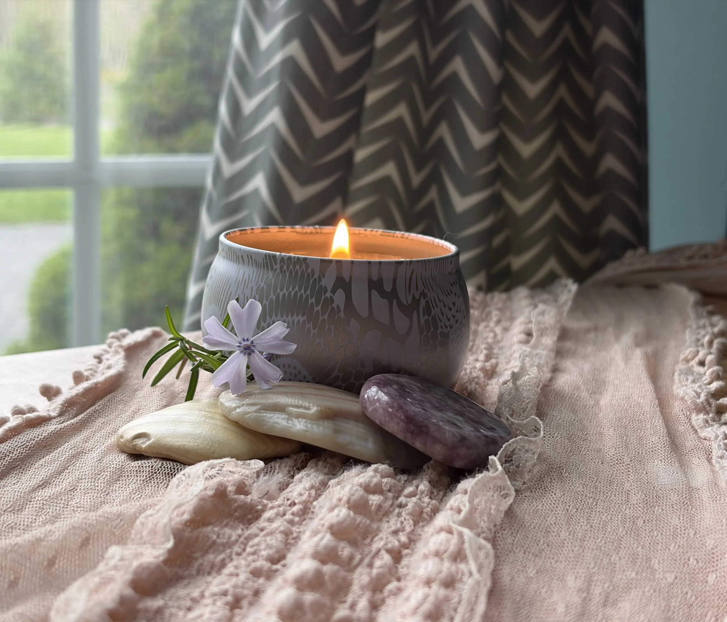 Lit candle amethyst crystal and blush throw in therapy office creating calming healing space