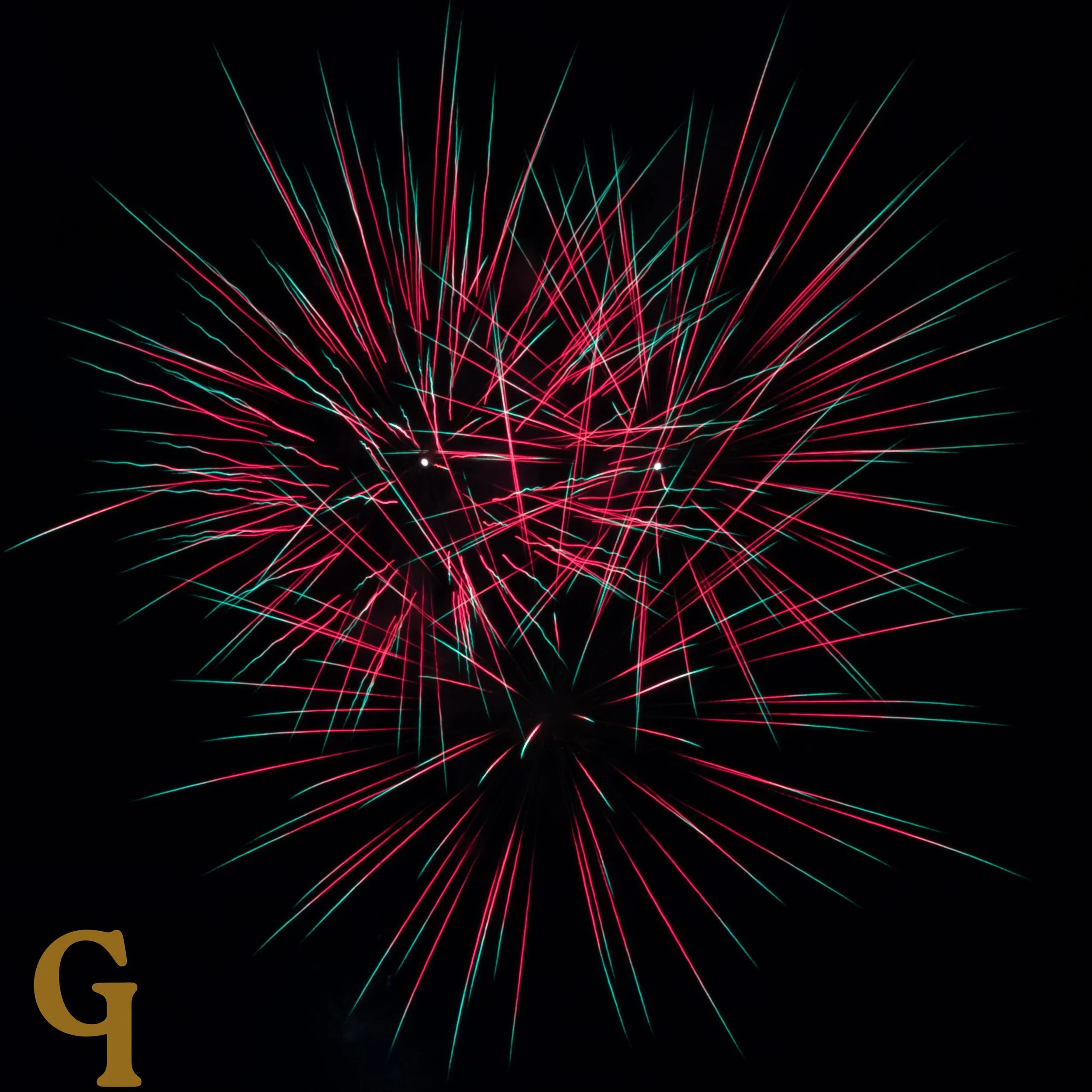 Colorful fireworks exploding against a black night sky with red and teal streaks.