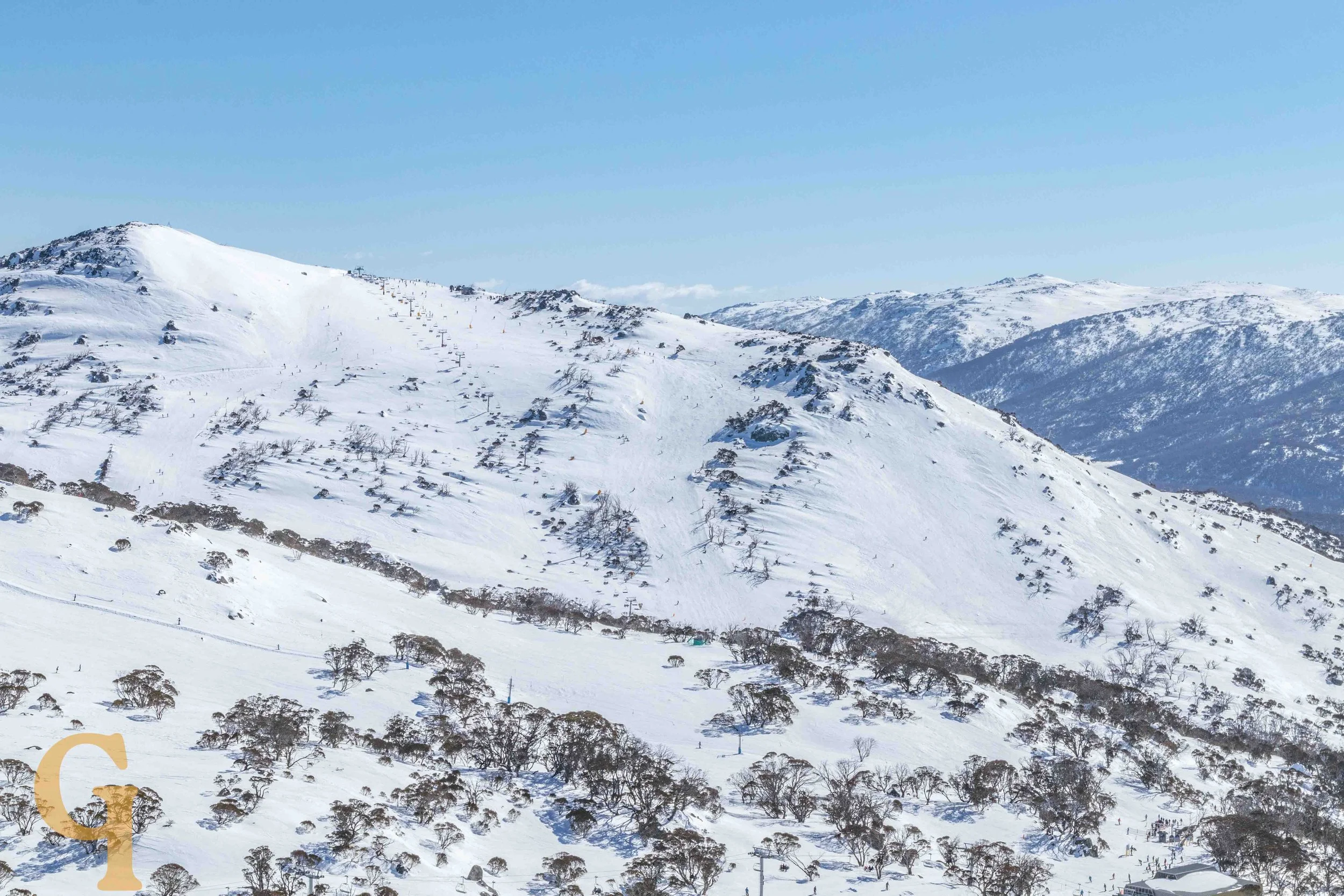 Snow-covered mountain landscape with ski slopes, ski lifts, and sparse trees.