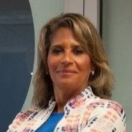 A woman with shoulder-length hair smiling, wearing a patterned blouse.