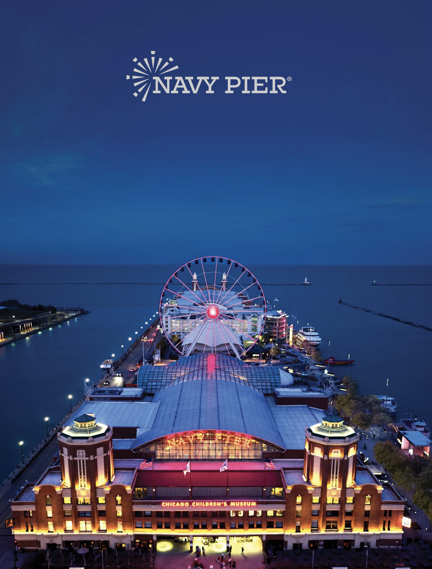 Night view of Navy Pier in Chicago, illuminated with colorful lights, with a Ferris wheel and the Chicago Children's Museum visible.