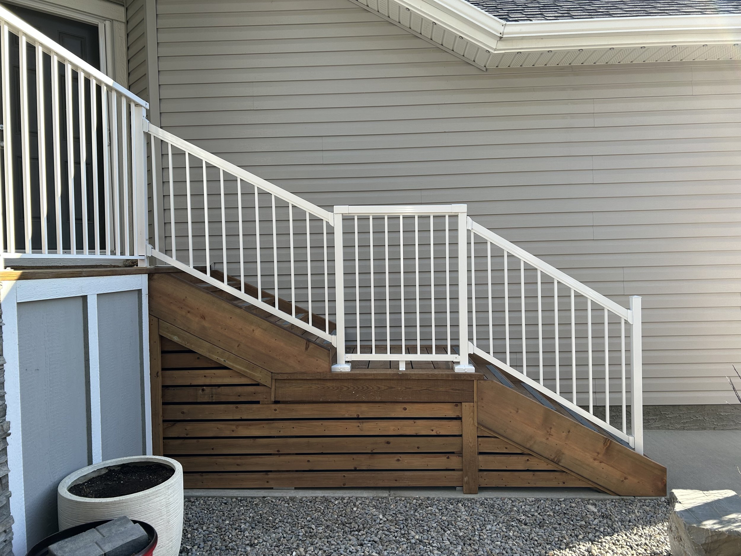 After pic of custom stairs with low rise with mid-level landing, railing and skirting for safe and comfortable main entrance access to home.