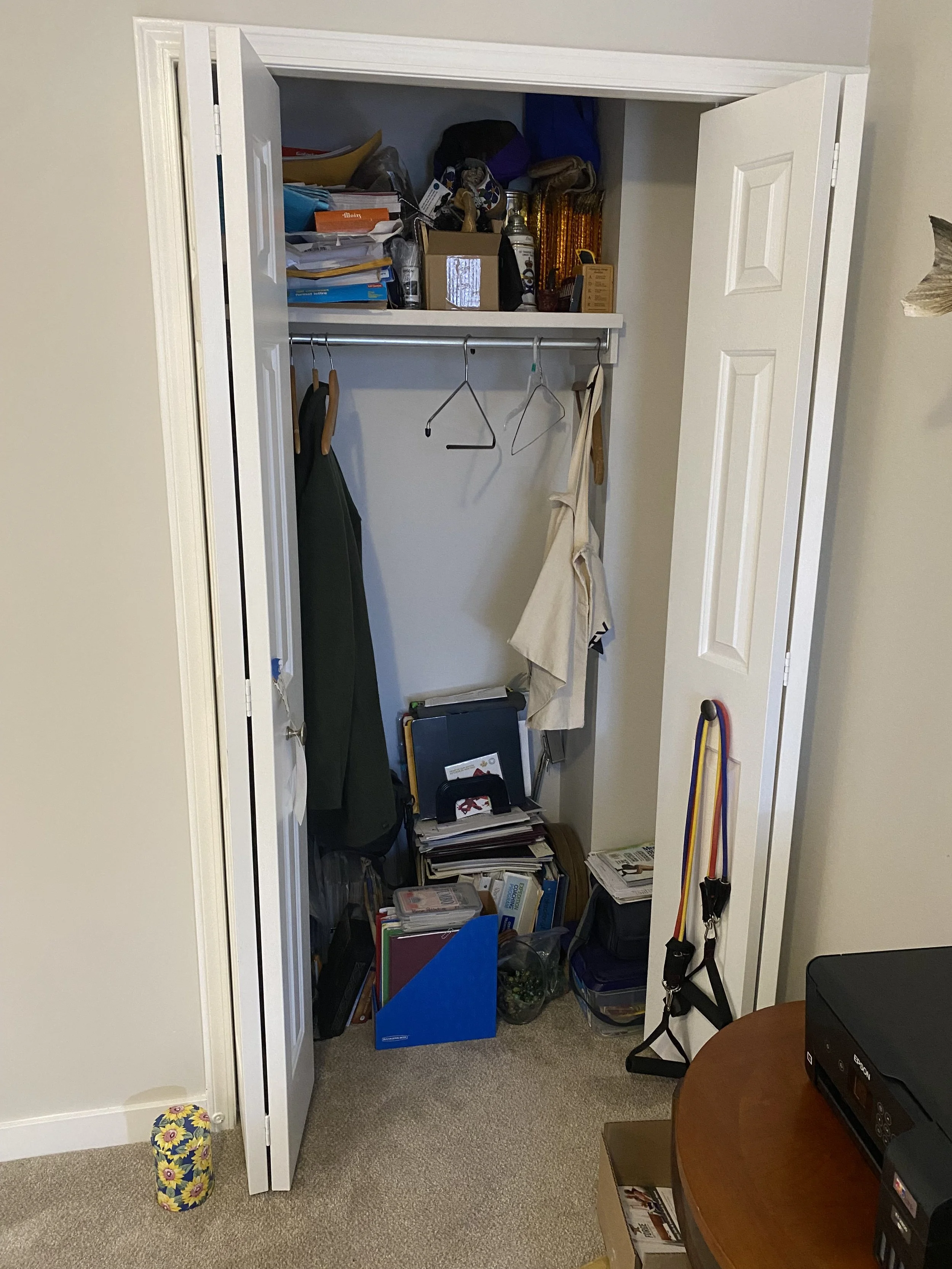 Before pic of standard, cluttered closet in a home office.