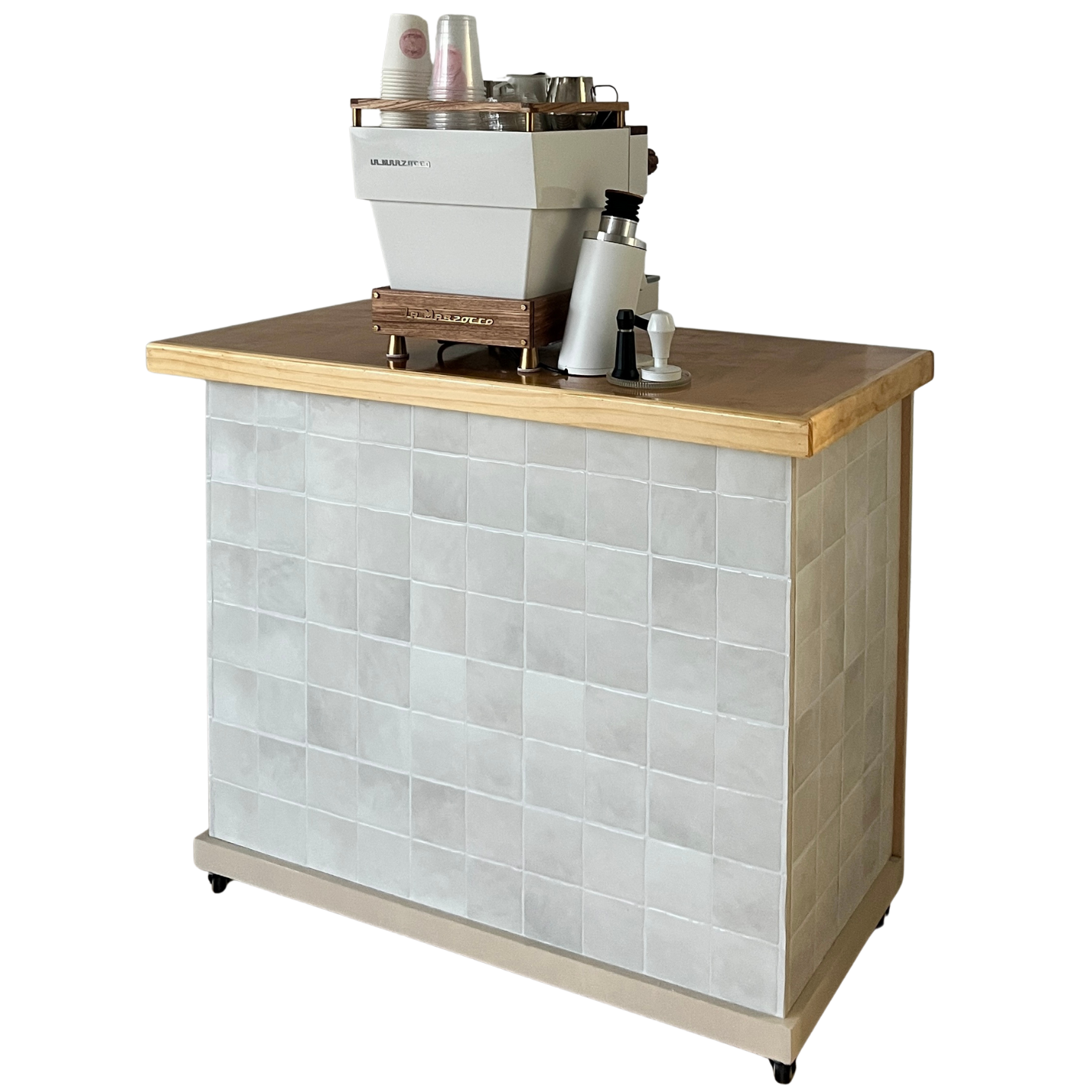 A coffee counter with a wooden top, tiled front, and a coffee machine with cups, lids, and accessories on top.