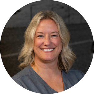 Circular profile image of a Vancouver Prosthetics & Orthotics employee with short blonde hair smiling, wearing a gray top in Vancouver, BC.