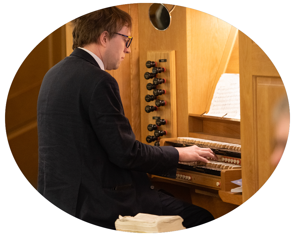 A man playing an organ or pipe organ in a wooden-paneled room.