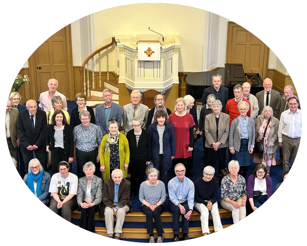 A large group of people gathered on the steps of a church or religious building, with a pulpit and piano in the background.