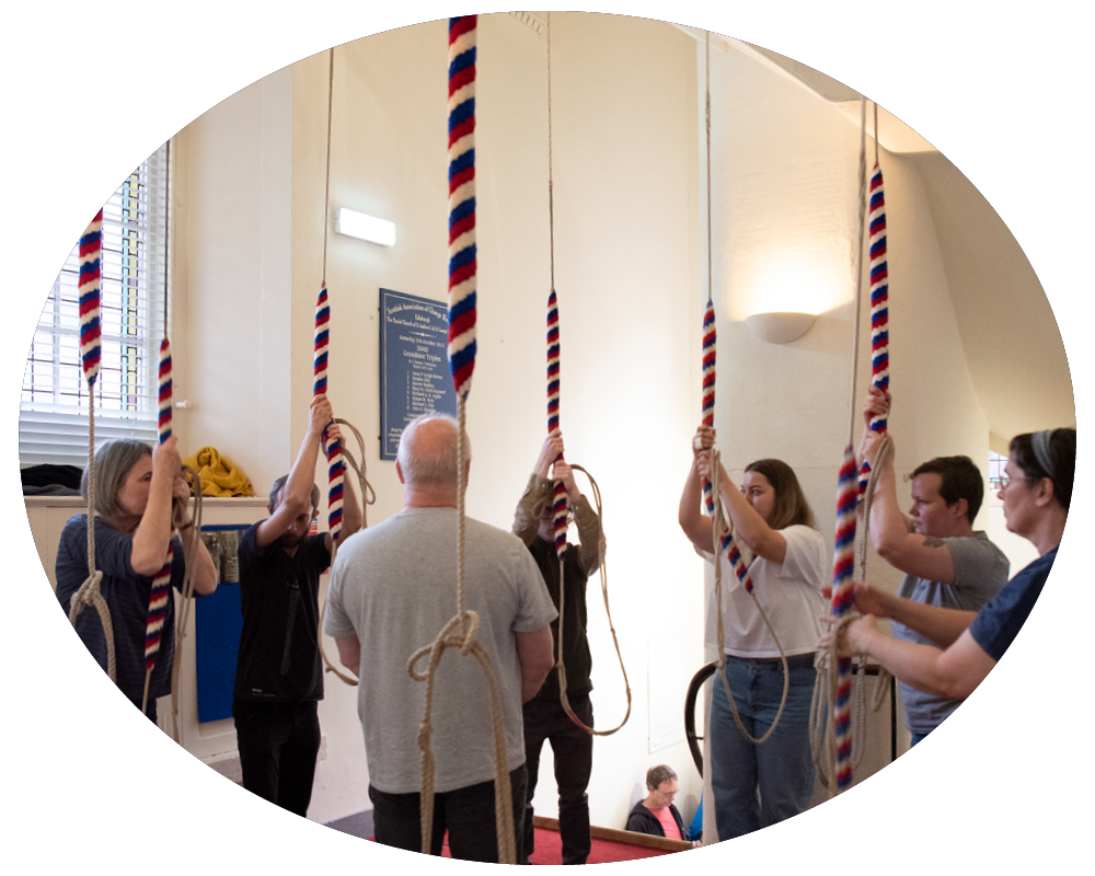 People participating in a team-building activity involving hanging from ropes on a wall inside a room.