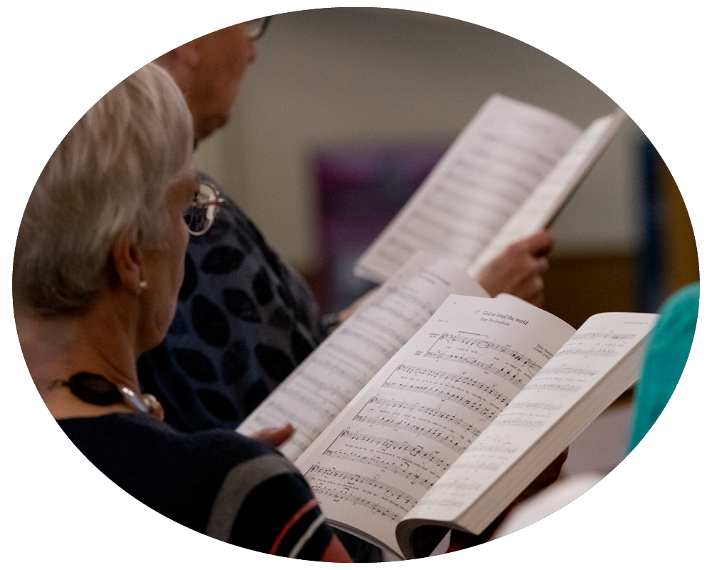 Three people reading sheet music in a music practice room or classroom.