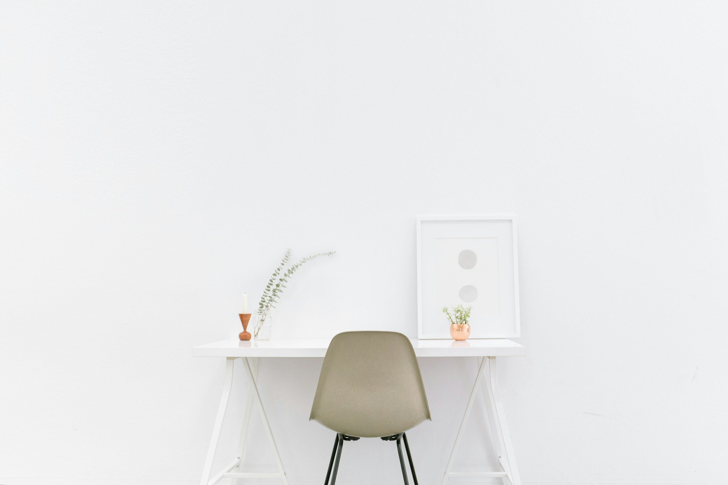 an image of a modern white desk and chair against the wall for a clean workspace look and feel.