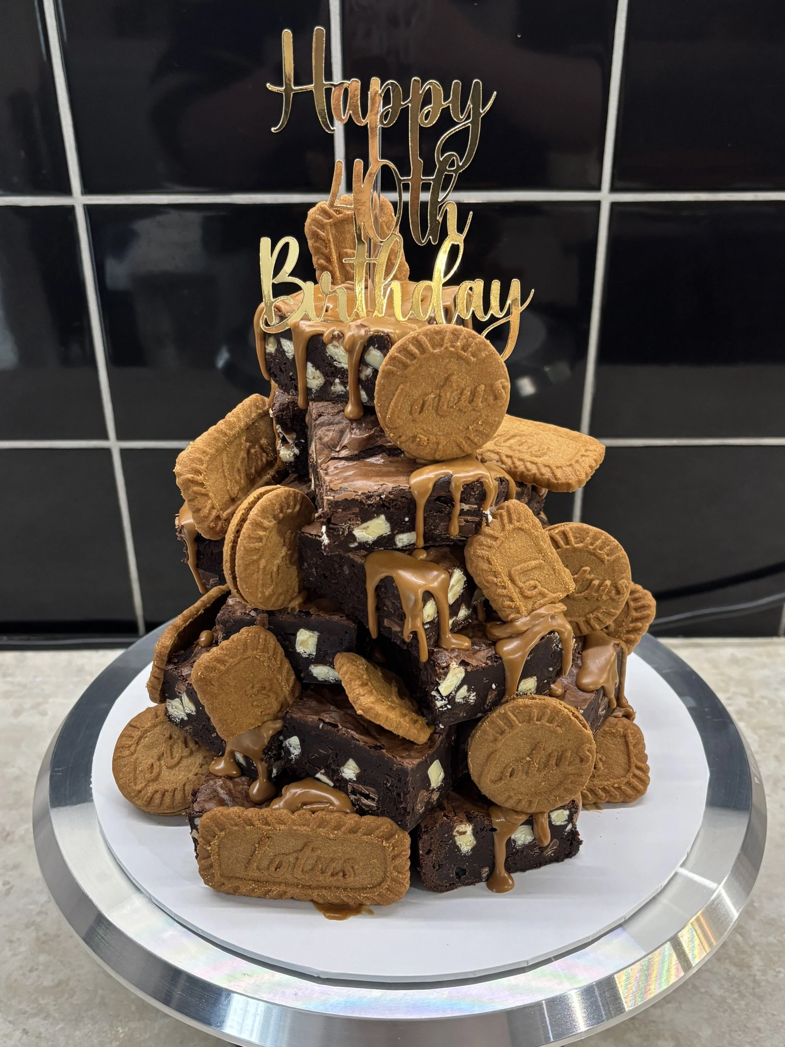 Chocolate fudge brownies topped with Lotus Biscoff cookies and caramel drizzle, arranged in a pyramid shape with a 'Happy 40th Birthday' topper.