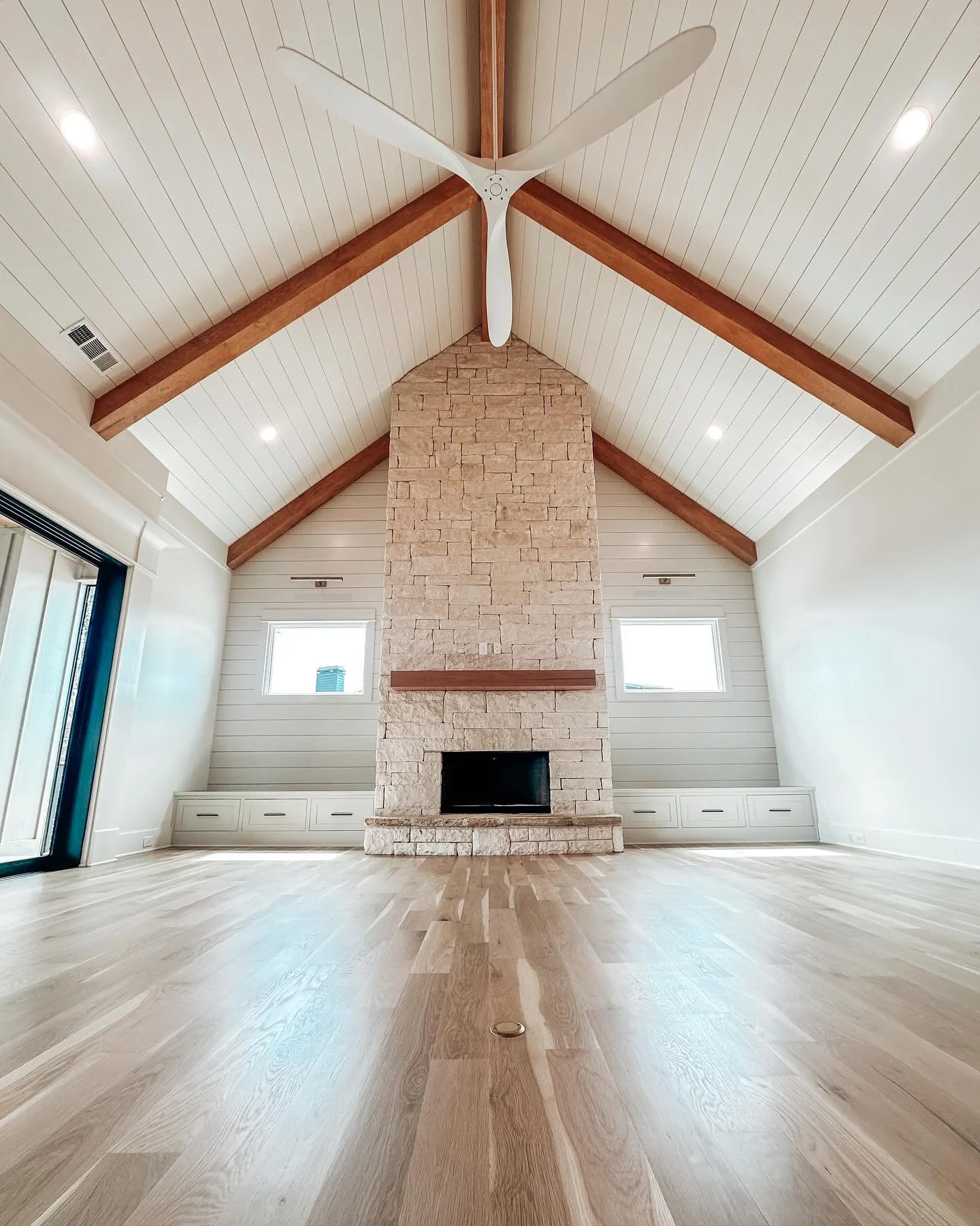 Mixing textures and earthy tones can help bring spaces to life. This inviting family room achieves that look by including a Texas Limestone fireplace and wooden beams.