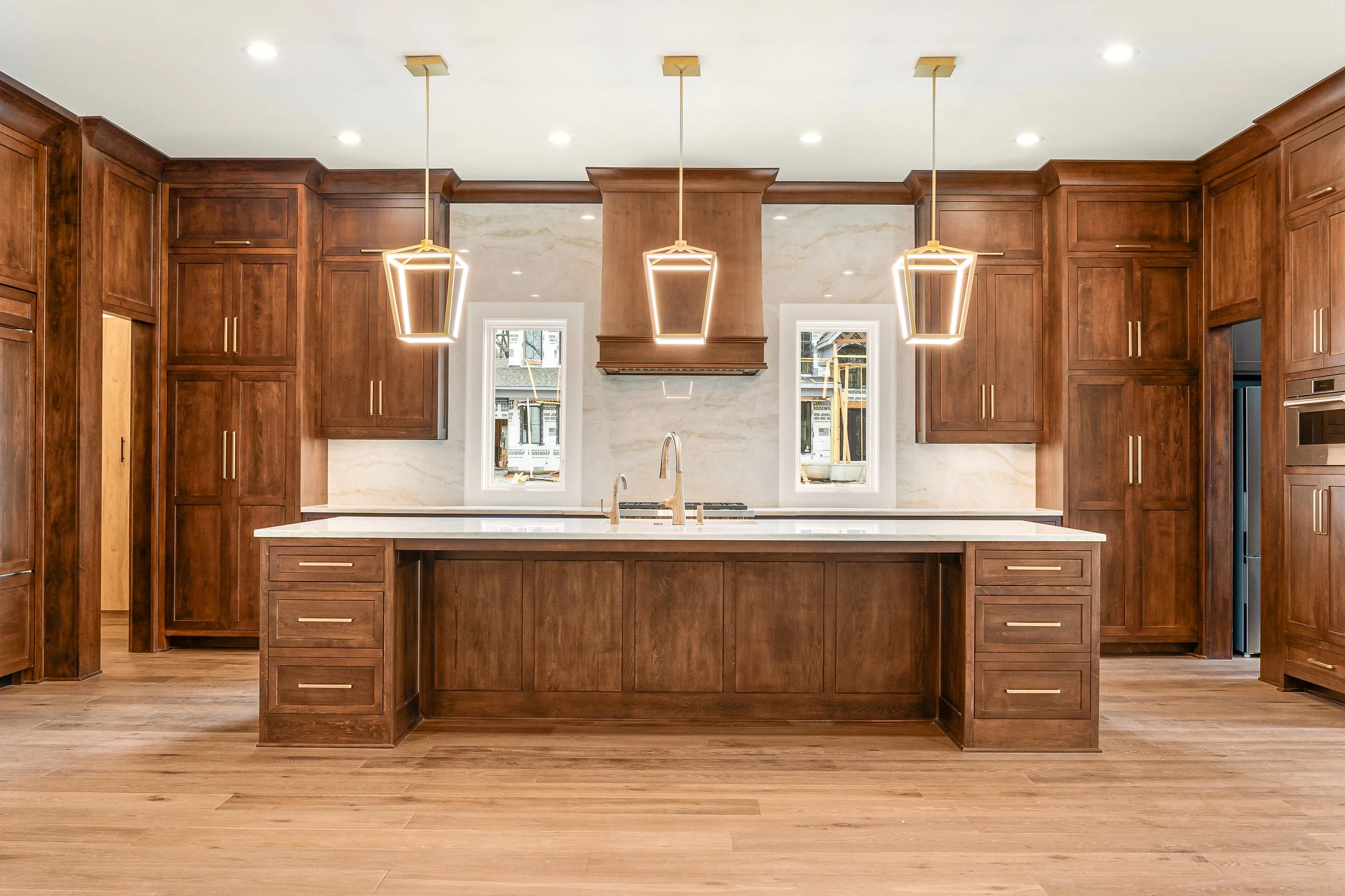 Modern kitchen with wooden cabinets, a central island, and pendant lighting fixtures.