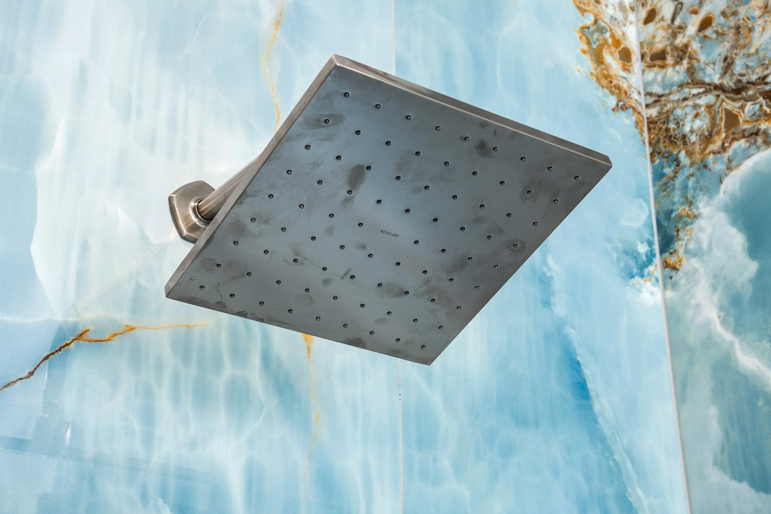 A large rectangular showerhead mounted on a wall with a blue marble pattern.