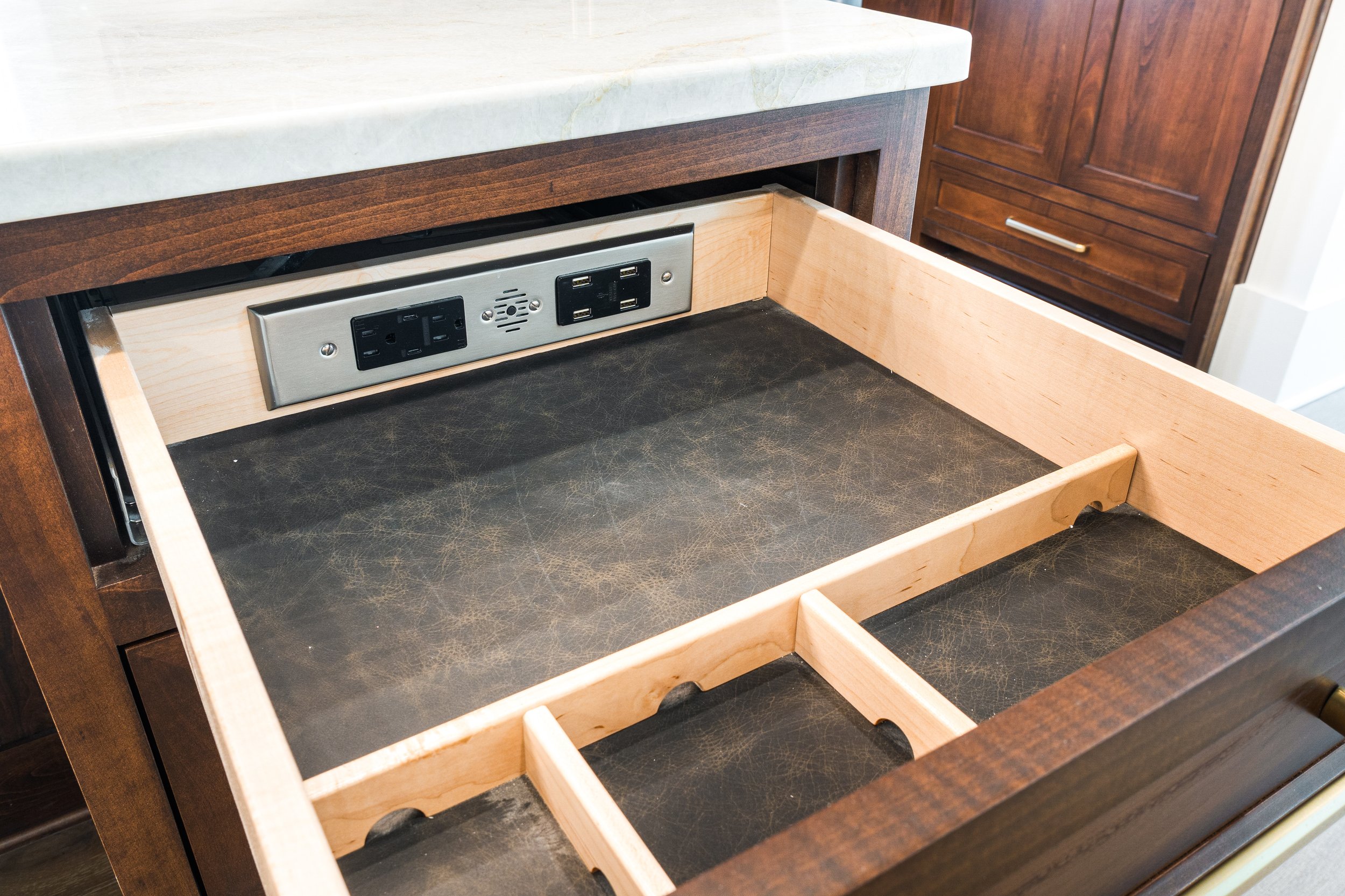 Open kitchen drawer with electrical outlets inside, wooden frame, no utensils.