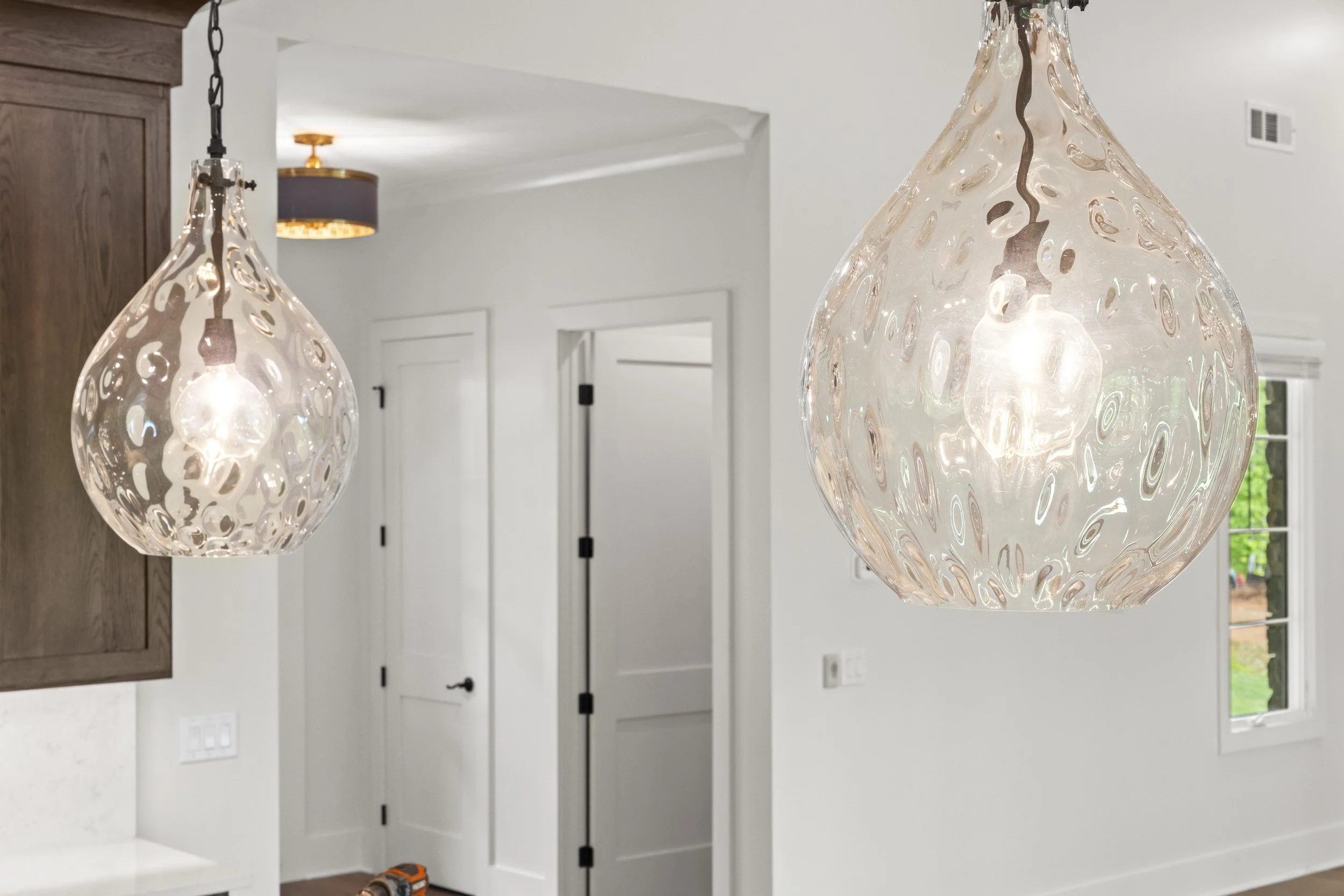 Two glass pendant lights hanging from the ceiling in a bright, modern kitchen or dining area.