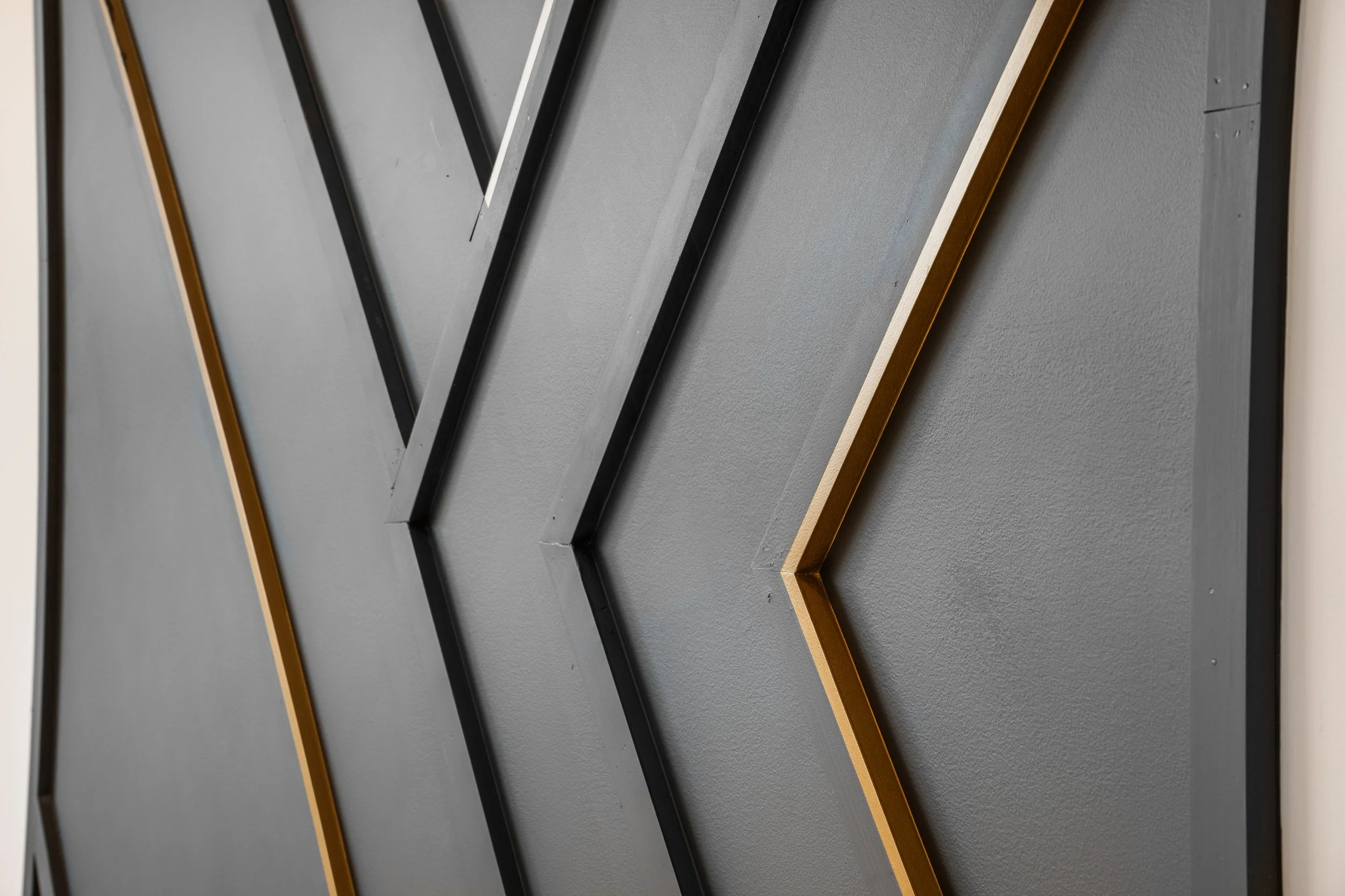 Close-up of black and gold picture frames with a matte dark gray background.