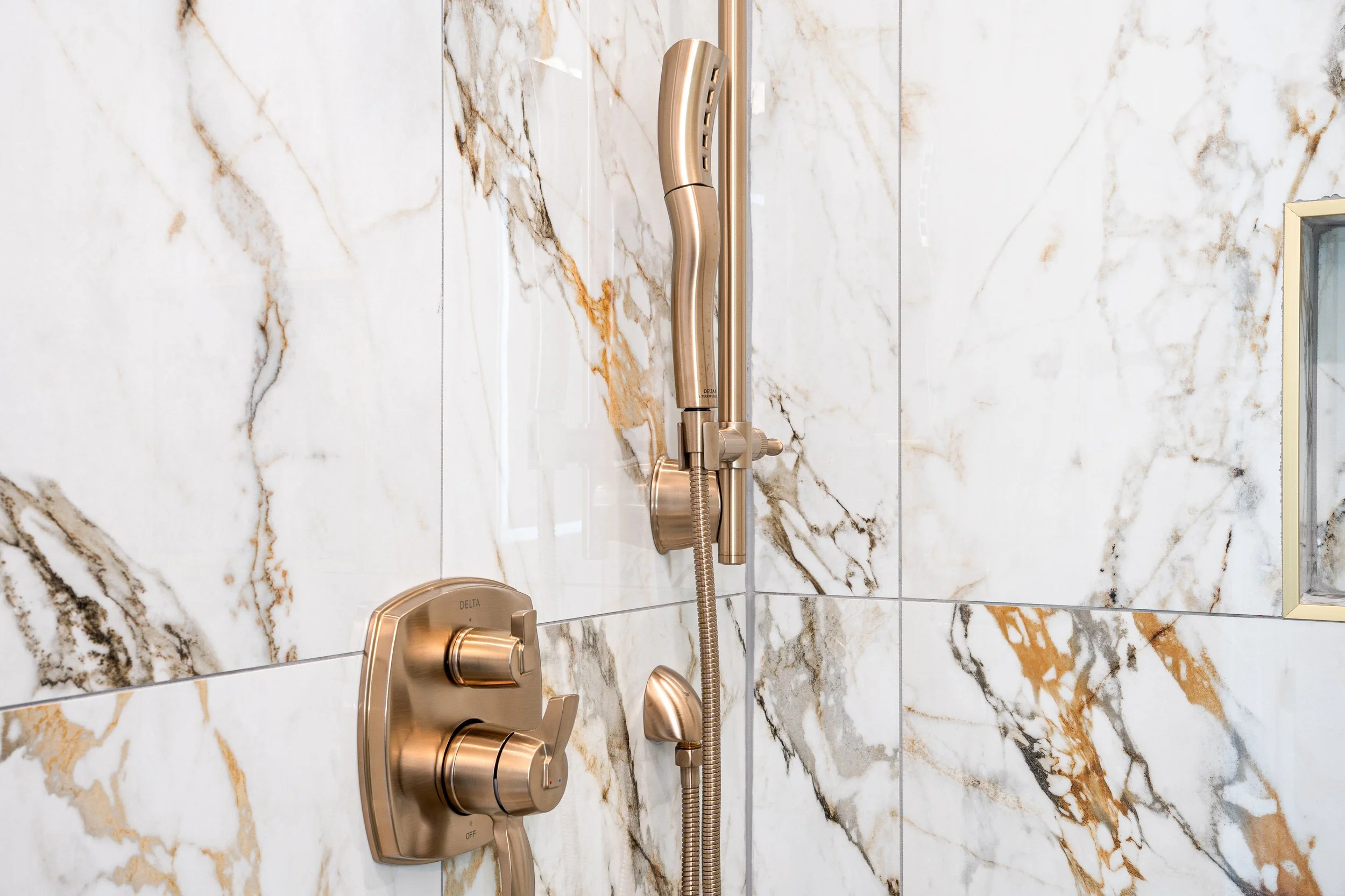 Close-up of a modern shower fixture with a marble wall background.