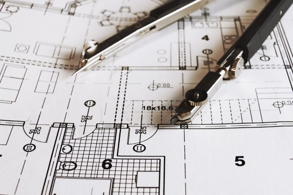 Architectural blueprint with a compass and a scale ruler on top.