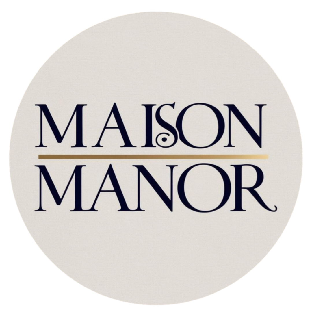 Logo with the text 'MAISON MANOR' in dark blue font, with a gold line separating the words, on a light background.